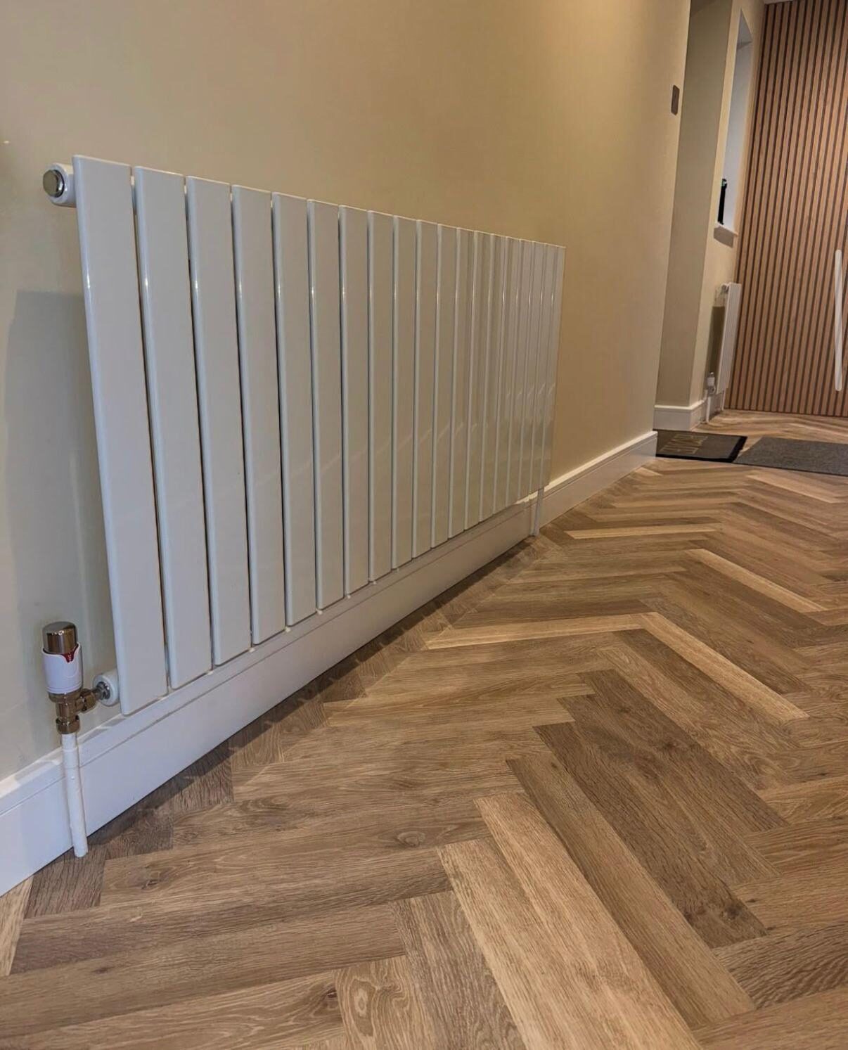 Designer flat-panel white radiator on a herringbone hallway floor — modern heating upgrade by On-Tap Plumbing & Heating