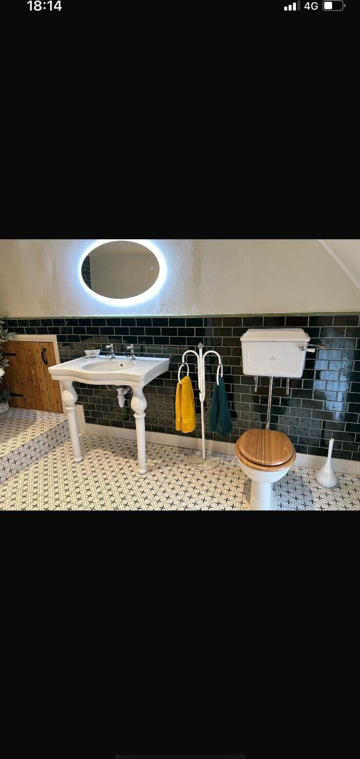 Traditional bathroom installation with console basin, dark green metro tiles and patterned encaustic floor by On-Tap Plumbing & Heating